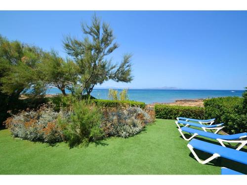 聖佩德羅科羅尼亞的住宿－Belvilla by OYO Embat，两把蓝色椅子坐在靠近海洋的草地上