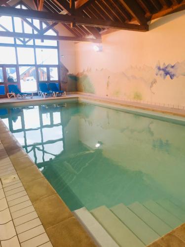 - une piscine remplie d'eau dans un bâtiment dans l'établissement Les sybelles, à La Chal