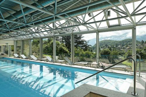a swimming pool with chairs and a view of the mountains at Hotel Eden Spiez in Spiez