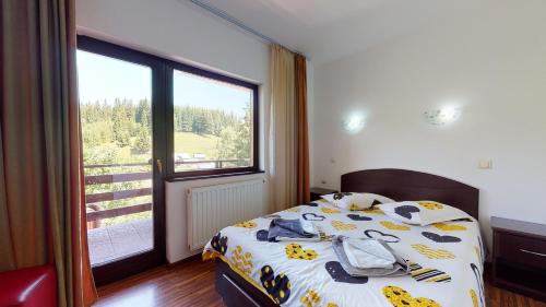 a bedroom with a bed and a large window at Perla Sarisorului in Sărişor