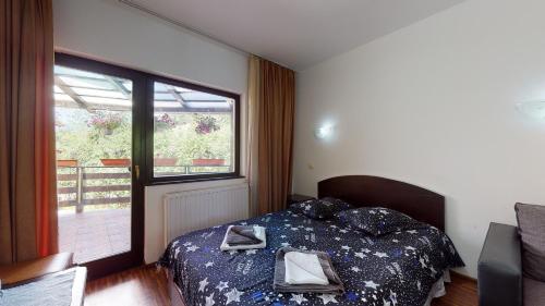 a bedroom with a bed and a large window at Perla Sarisorului in Sărişor