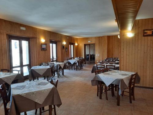 a restaurant with tables and chairs with white tablecloths at Albergo Rifugio La Grande Baita in Cutigliano