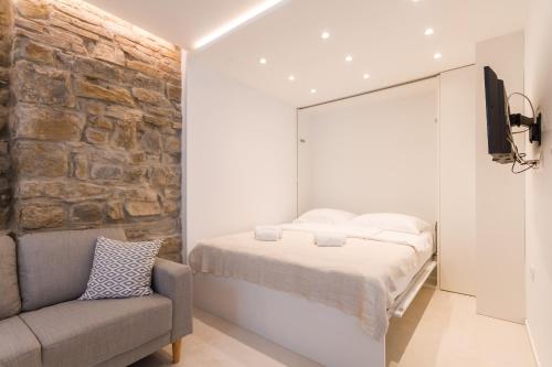 um quarto com uma cama e uma parede de pedra em Studio Apartment Tetida by Locap Group em Piran