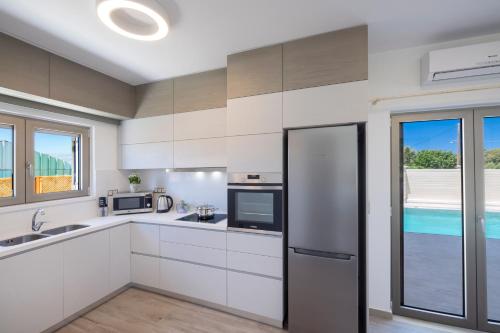 a kitchen with white cabinets and a stainless steel refrigerator at Villa Persephone in Tavronitis