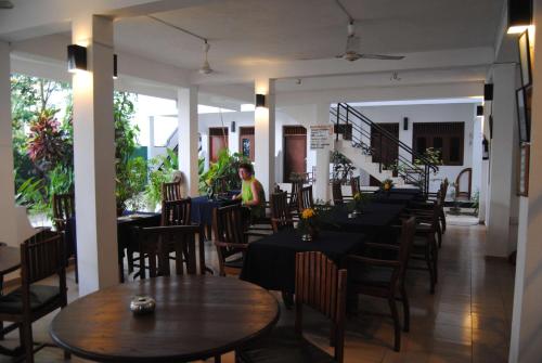 a restaurant with tables and chairs and a person in the background at Unawatuna Beach Bungalow - in Unawatuna