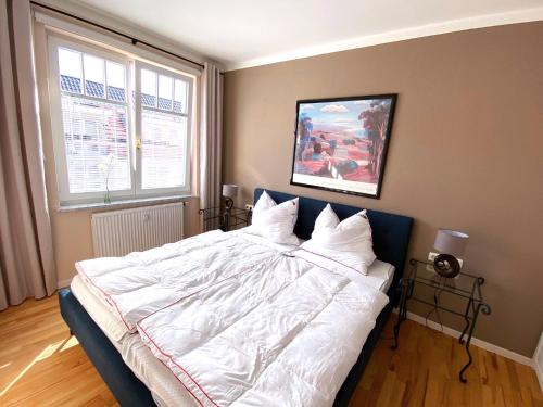 ein Schlafzimmer mit einem großen Bett mit weißer Bettwäsche und Kissen in der Unterkunft Appartement Dünenstraße in Kühlungsborn