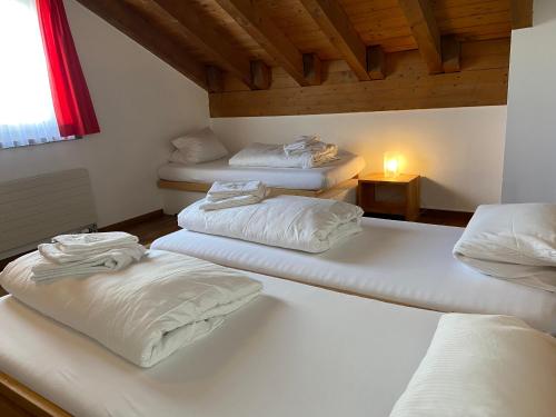 three white beds in a room with a window at Berggasthaus Piz Calmot in Andermatt