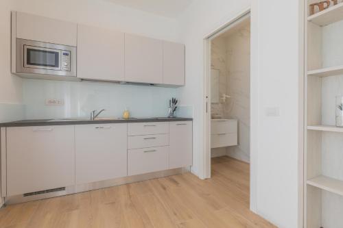 a white kitchen with a sink and a microwave at Casa LiLu by Comorooms in Como