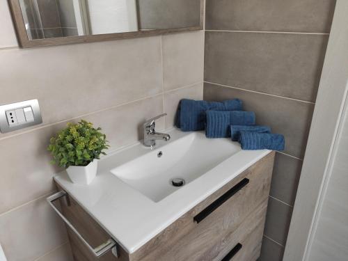 - un lavabo blanc dans la salle de bains avec des serviettes bleues dans l'établissement Antica Dogana Apartments, à Terracine