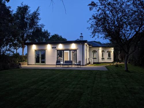 a white house with two chairs in a yard at Crossing Cottage Sleeps 6 Parking, Family & Contractors Newark in Staythorpe