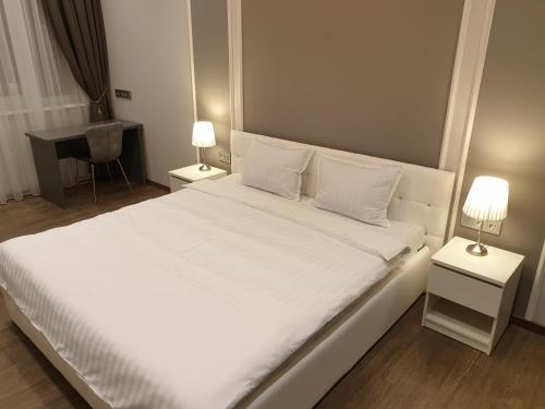 a bedroom with a large white bed with two lamps at MARBEO 5 Star Luxury Suites - Peldu in Liepāja