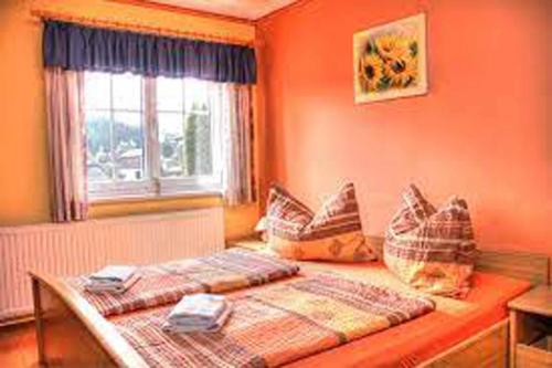 1 dormitorio con 2 camas, paredes de color naranja y ventana en Gasthof Hofbauer en Jagenbach