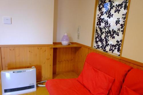 a room with a red chair and a television at Villa Ensoleille in Fujikawaguchiko