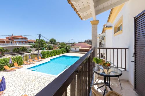 a balcony with a swimming pool and a table and chairs at Dora Pool Studios by Konnect,150m from the Beach in Agios Georgios