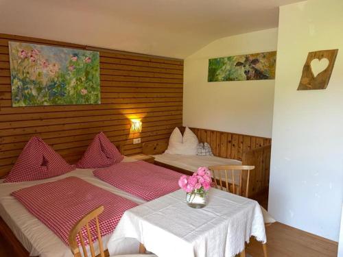 a bedroom with two beds and a table with flowers on it at Oberachenhof in Ellmau