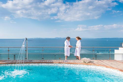a man and woman standing next to a swimming pool at Hotel & Spa Terraza 4 Sup in Roses