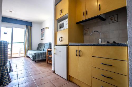 cocina con armarios amarillos, fregadero y sofá en Hotel Apartamentos Mojácar Beach, en Mojácar