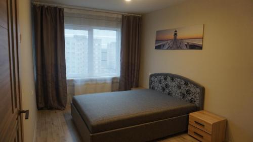 um pequeno quarto com uma cama e uma janela em Sunny Ventspils 27 em Ventspils