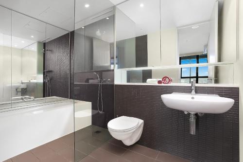 a bathroom with a toilet and a sink and a tub at Stylish 1 bdrm Camperdown - Car park, Gym & Pool in Sydney