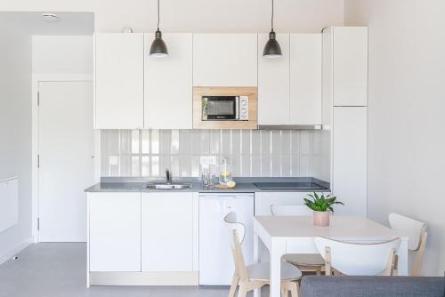 a kitchen with white cabinets and a table and chairs at BAO 1 / APARTAMENTO CON JARDÍN in Somo