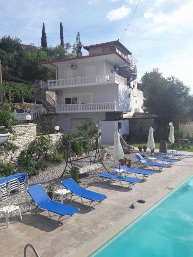 a group of chairs and umbrellas next to a pool at Sezar's - Niko & Mimoza Qesari in Qeparo