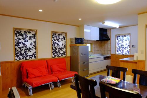 a living room with a red couch and a kitchen at Villa Ensoleille in Fujikawaguchiko