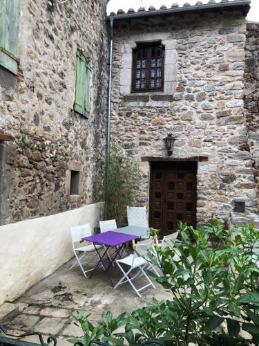 une table et des chaises violettes devant un bâtiment dans l'établissement Les Maisons du Conflent, maisons familiales en pierre au coeur des remparts, à Villefranche-de-Conflent