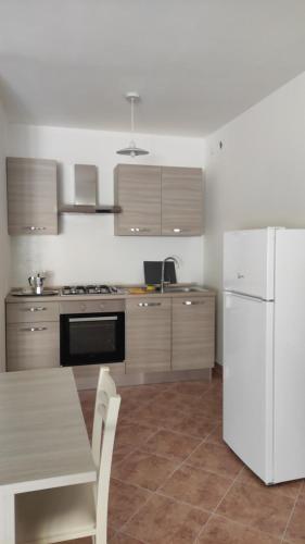 cocina con mesa y nevera blanca en Residence TANA - via Pasubio en Enego