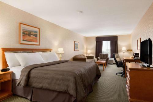 a hotel room with a bed and a television at Days Inn by Wyndham Saskatoon in Saskatoon