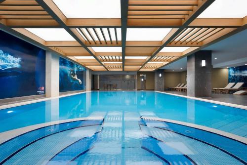 - une grande piscine d'eau bleue dans un bâtiment dans l'établissement Ramada Plaza By Wyndham Konya, à Konya