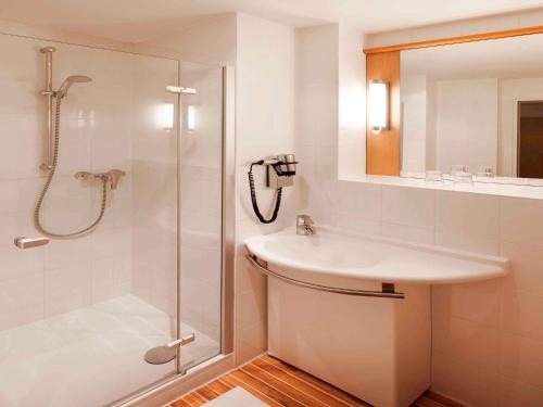 a white bathroom with a sink and a shower at ibis Hotel Nürnberg Altstadt in Nuremberg
