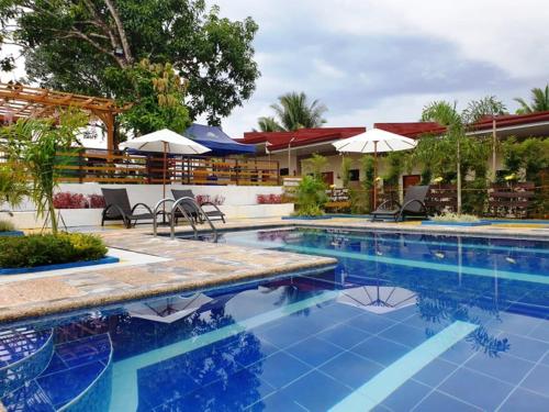 een zwembad in een resort met stoelen en parasols bij Villa Susane in Balamban