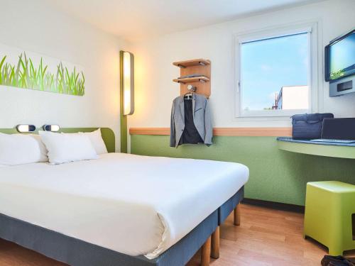 a bedroom with a large white bed and a window at Ibis Budget Versailles Coignieres in Coignières