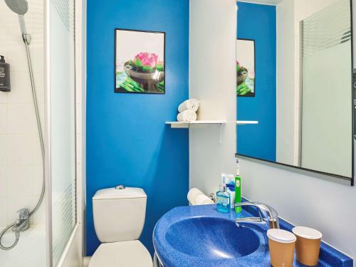 uma casa de banho azul com um WC e um lavatório em Ibis Budget Versailles Coignieres em Coignières