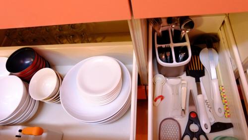 a cupboard filled with white plates and utensils at Villa Ensoleille in Fujikawaguchiko