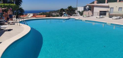 a large blue swimming pool with a view of the ocean at Appartement Quinta de Palames Sesimbra in Sesimbra