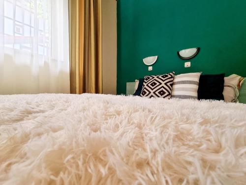 duże białe łóżko z zieloną ścianą i poduszkami w obiekcie Pensiunea Don Sergio w mieście Predeal