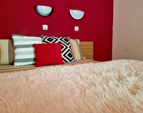 1 cama con almohadas y pared roja en Pensiunea Don Sergio, en Predeal