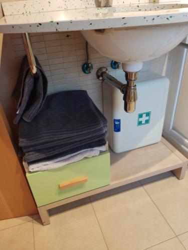 - un lavabo dans la salle de bains avec une pile de serviettes et une boîte sous celle-ci dans l'établissement La ventana de la catedral, à Burgos