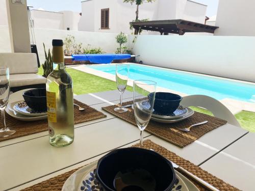 a table with a bottle of wine and glasses next to a pool at Aquavilla in Costa Teguise