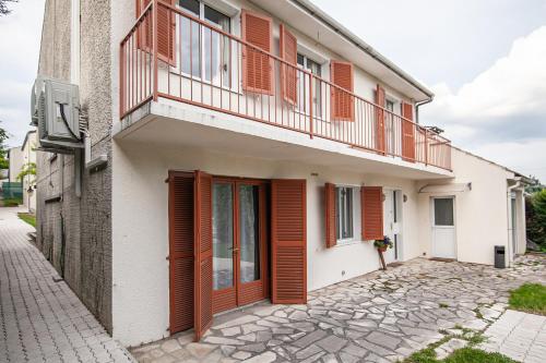 un edificio con puertas rojas y balcón en Grand Appartement de 3 pièces, en Pierrelaye