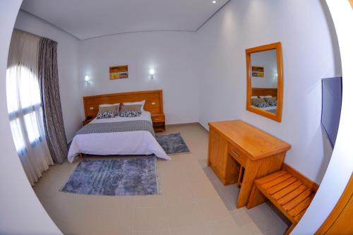a bedroom with a bed and a mirror at DAR AMMAR in El Jem