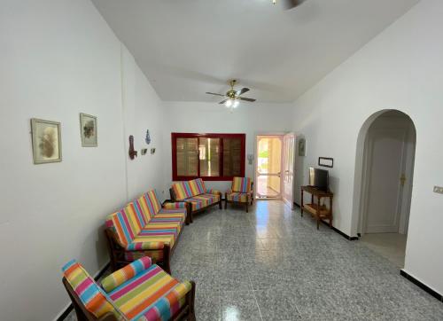 een woonkamer met stoelen en een plafondventilator bij A cheerful chalet villa few steps to the beachside in Marsa Matruh
