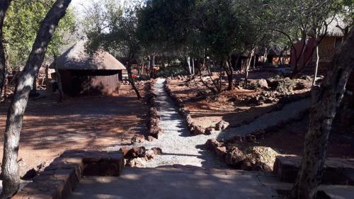 a dirt road with a building and some trees at ThabaNkwe Bushveld Inn in Thabazimbi