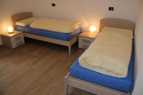 two beds in a small room with two lamps at Appartamenti Dany in Arabba