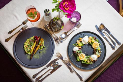 two plates of food on a table with silverware at Landhotel Häuserl im Wald in Gröbming