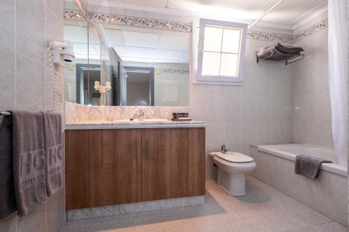 a bathroom with a sink and a toilet and a tub at HG Jardín de Menorca in Son Bou
