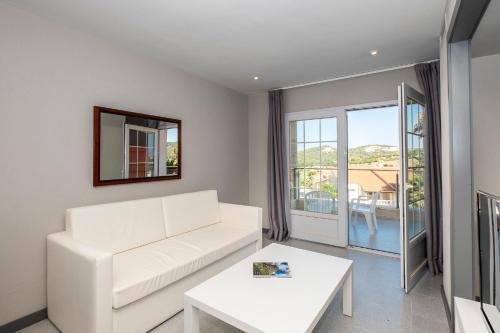 a white living room with a white couch and a table at HG Jardín de Menorca in Son Bou