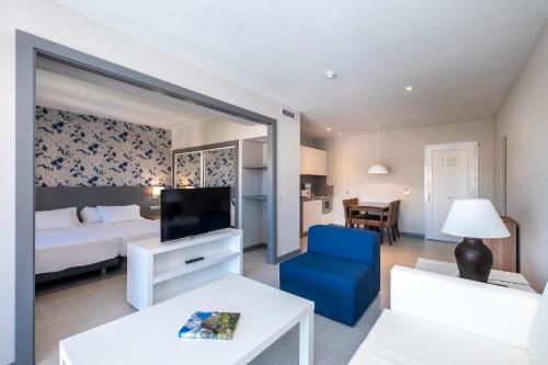 a hotel room with a bed and a blue chair at HG Jardín de Menorca in Son Bou