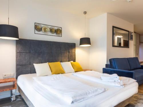 a bedroom with a large bed and a blue chair at VacationClub - Sand Hotel Apartment 201 in Kołobrzeg